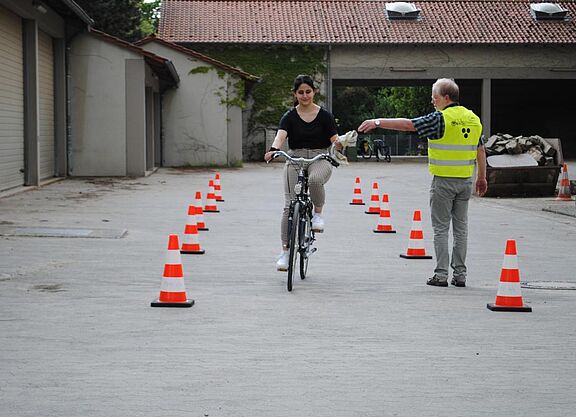 Frau fährt mit Fahrrad und nimmt Tuch von Lehrer entgegen